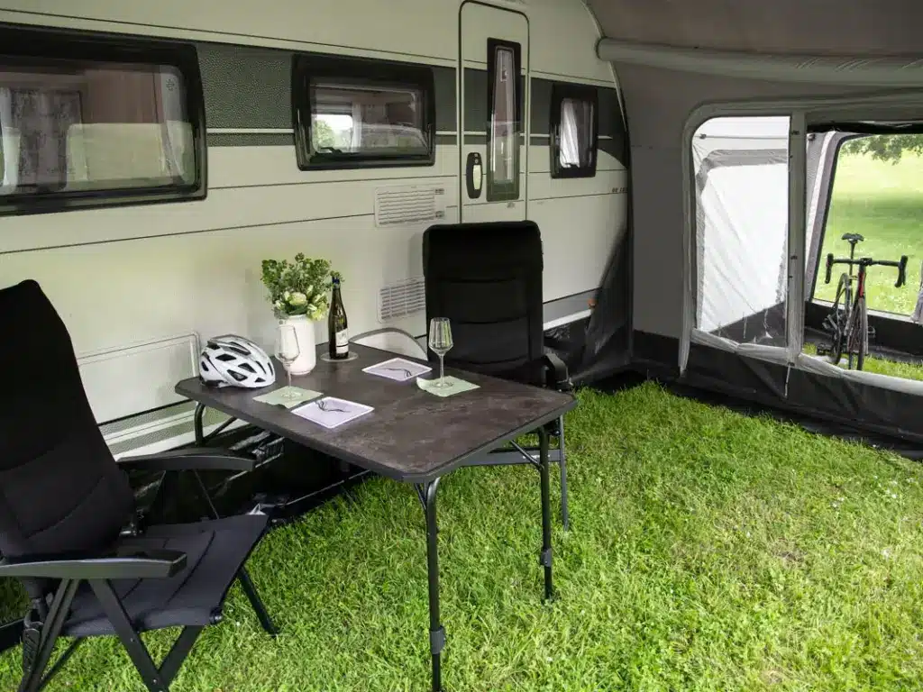 Campingplatz mit Wohnwagen, Tisch und Fahrradausrüstung.