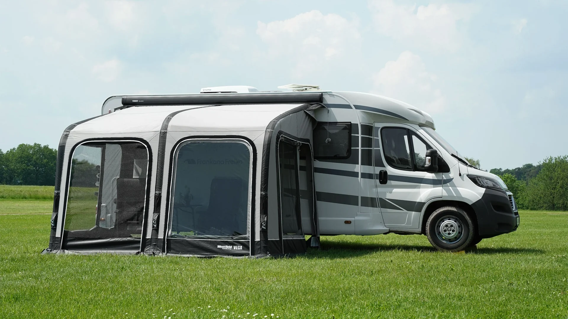 Wohnmobil mit Vorzelt auf Wiese geparkt