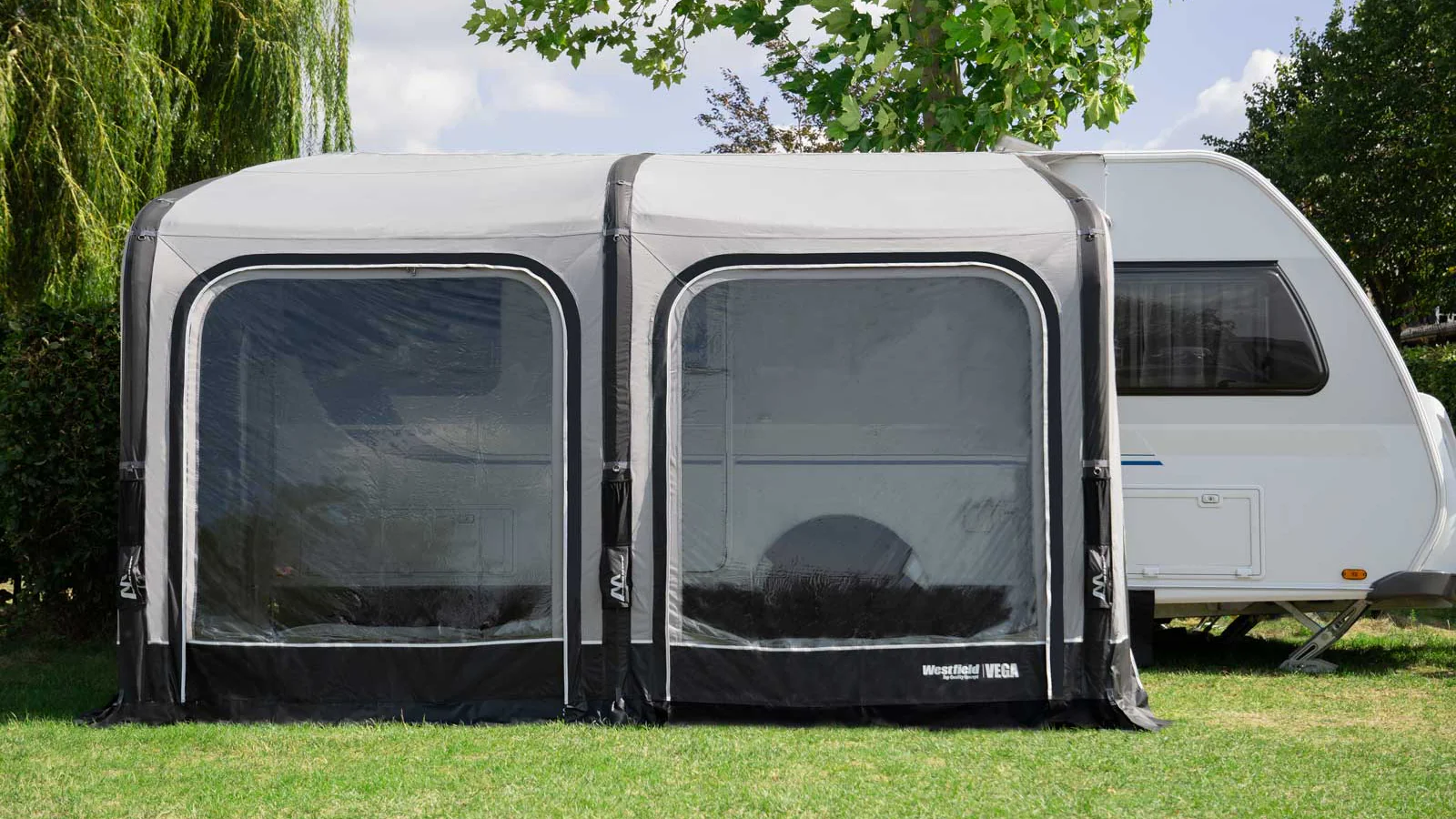 Wohnwagen mit grauem Vorzelt auf Wiese