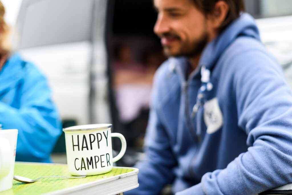 Mann mit Tasse 'Happy Camper' im Freien