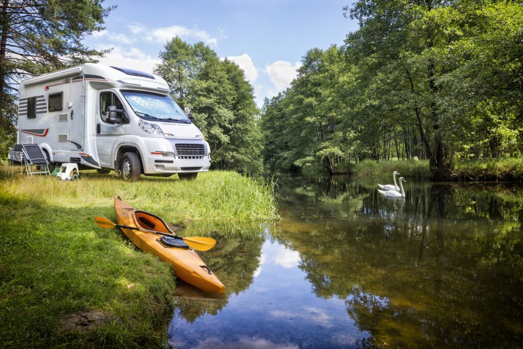 Wohnmobil am Fluss mit Kajak und Schwänen