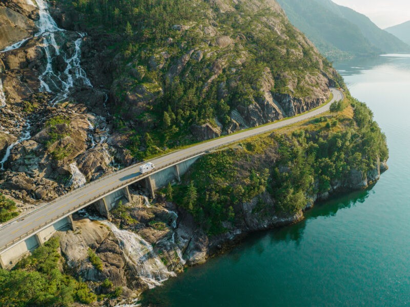 Wohnmobil fährt über Brücke in malerischer Berglandschaft.